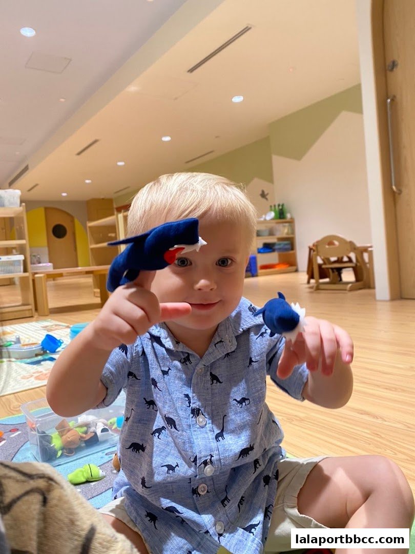 A young child plays with shark finger puppets in a bright, child-friendly learning environment.