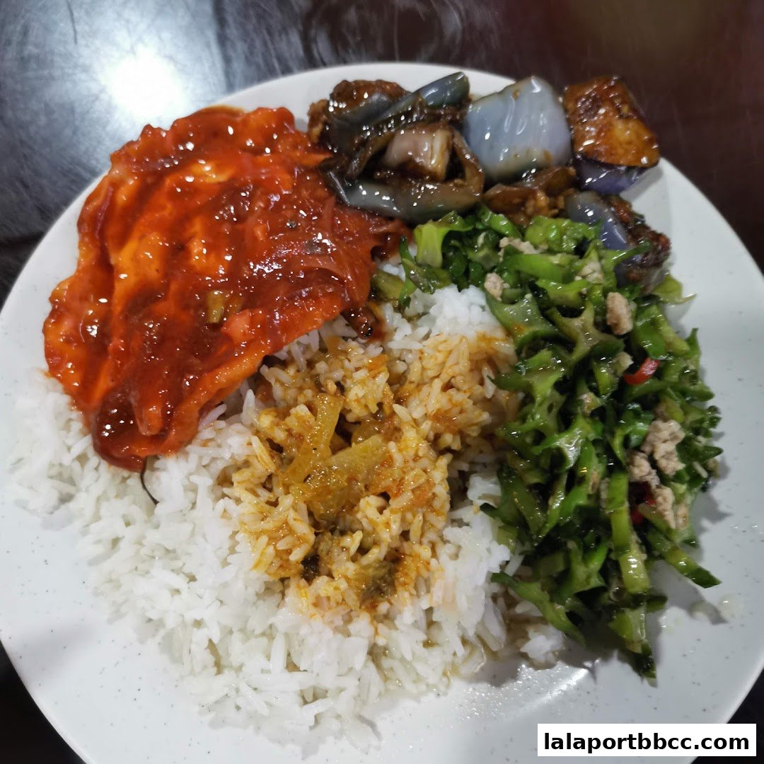 A plate of rice with various toppings including a saucy dish, vegetables, and eggplant.