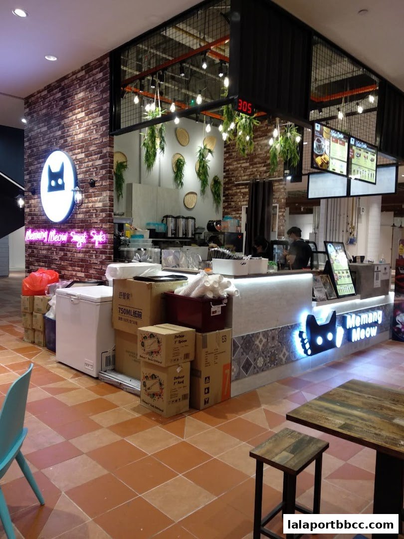 A brightly lit cafe counter with a neon cat logo and seating area.