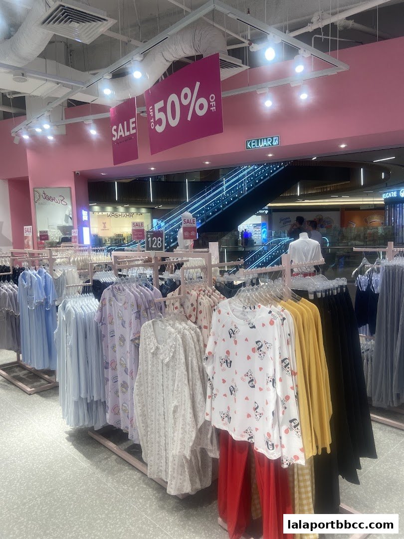 A brightly lit clothing store interior with racks of colorful pajamas and sale signs.