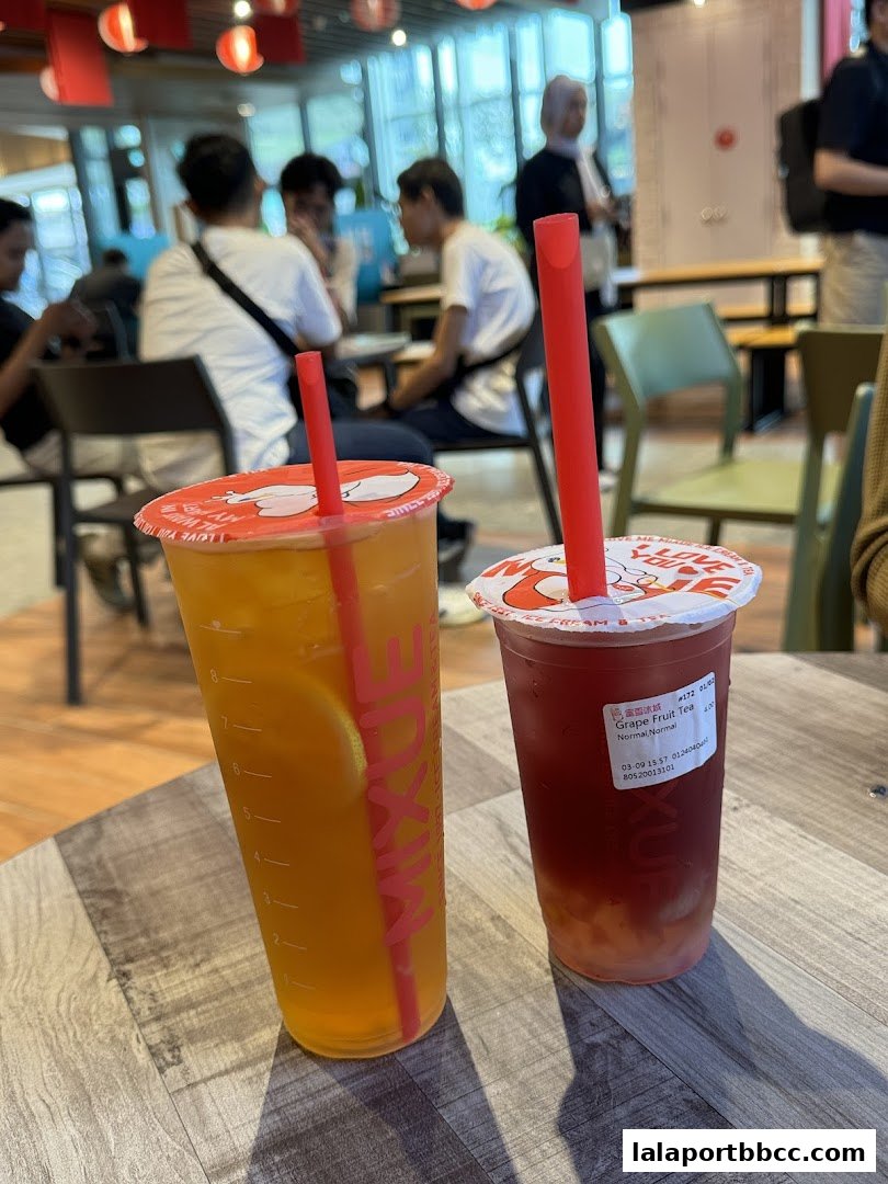 Two refreshing MIXUE drinks, one orange and one grape fruit tea, on a table.