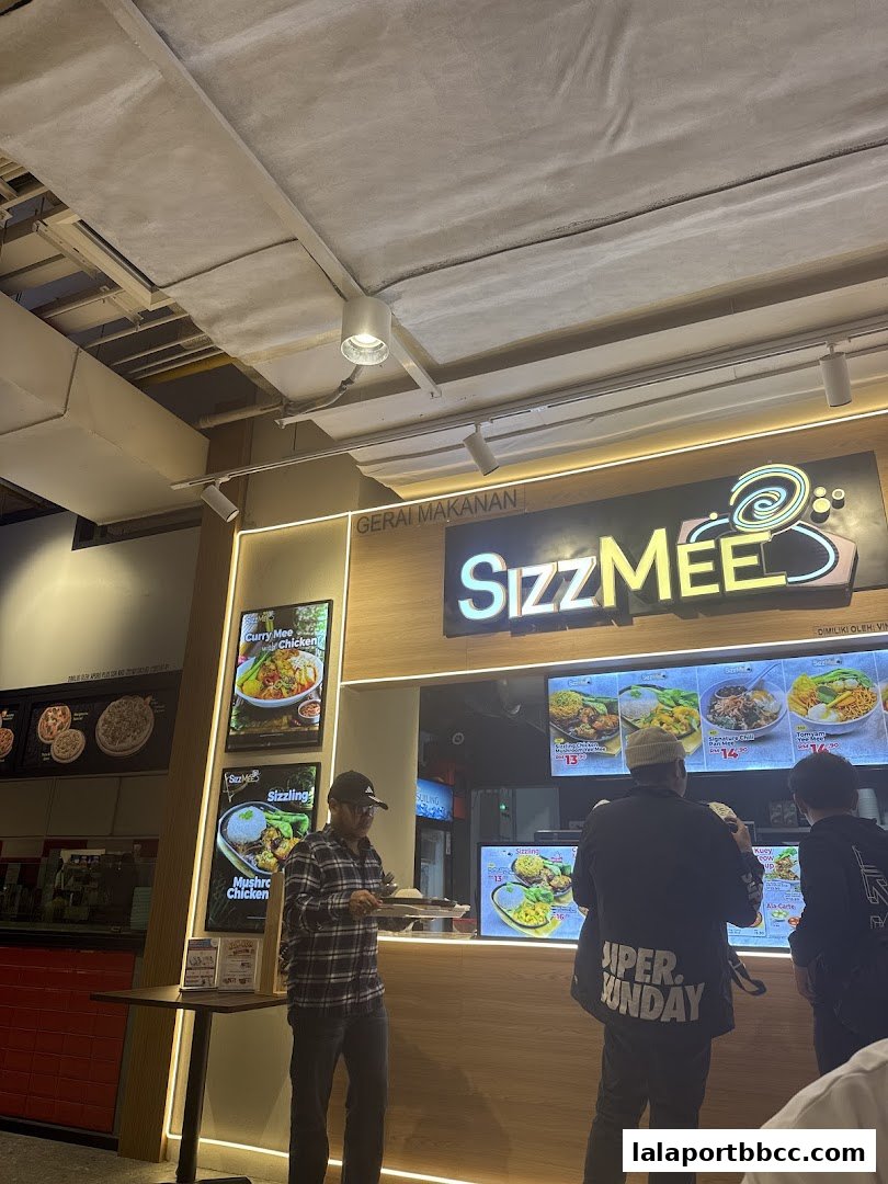 People ordering food at a Sizz Mee restaurant with illuminated menu boards.