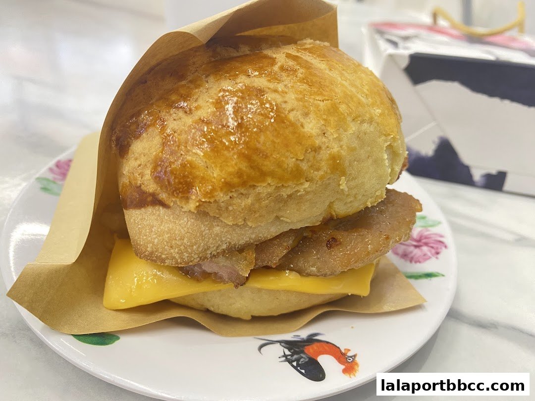 A close-up of a delicious pork chop bun with melted cheese on a decorative plate.