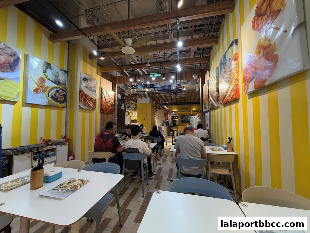 Interior of a restaurant with yellow and white striped walls, featuring food images and diners.