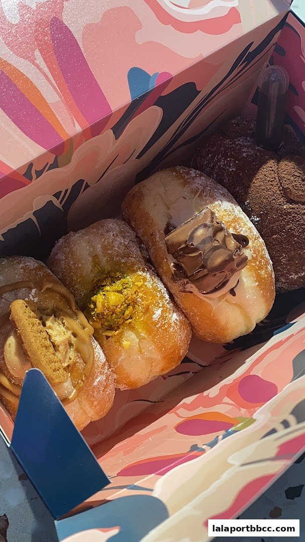 A box of assorted donuts with various toppings, including chocolate and pistachios.