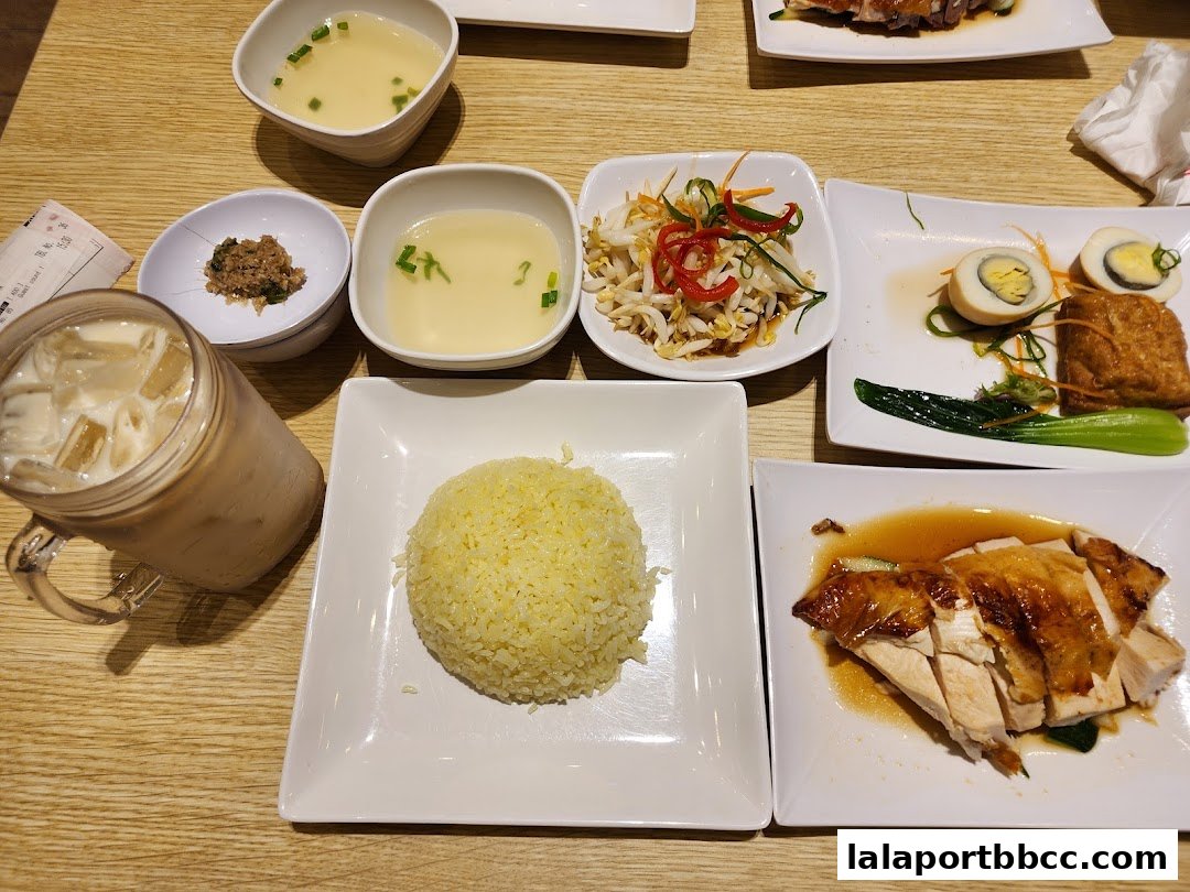 A table laden with delicious chicken rice, soup, side dishes, and a refreshing iced drink.