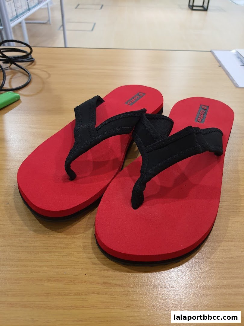 A pair of red and black flip-flops with the 'Lotto' logo displayed.