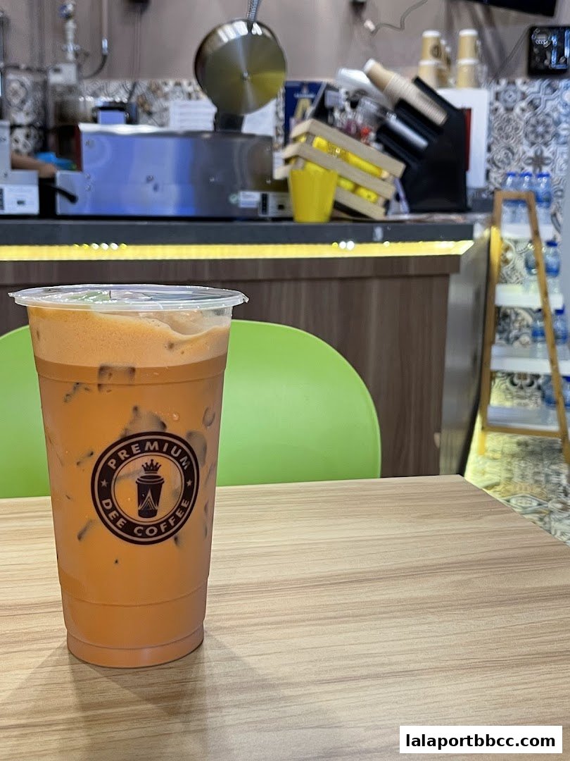 A refreshing iced Thai milk tea with the Dee Coffee logo on the cup.