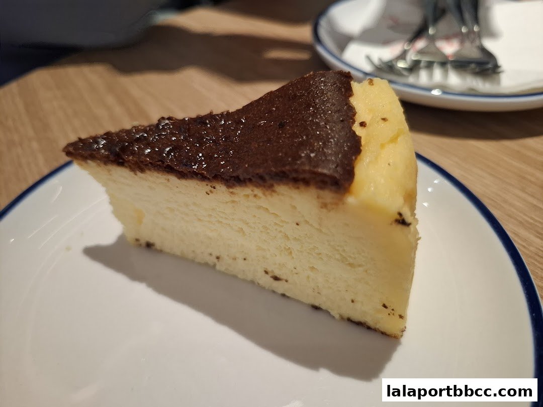 A slice of burnt cheesecake with a creamy texture on a white plate.