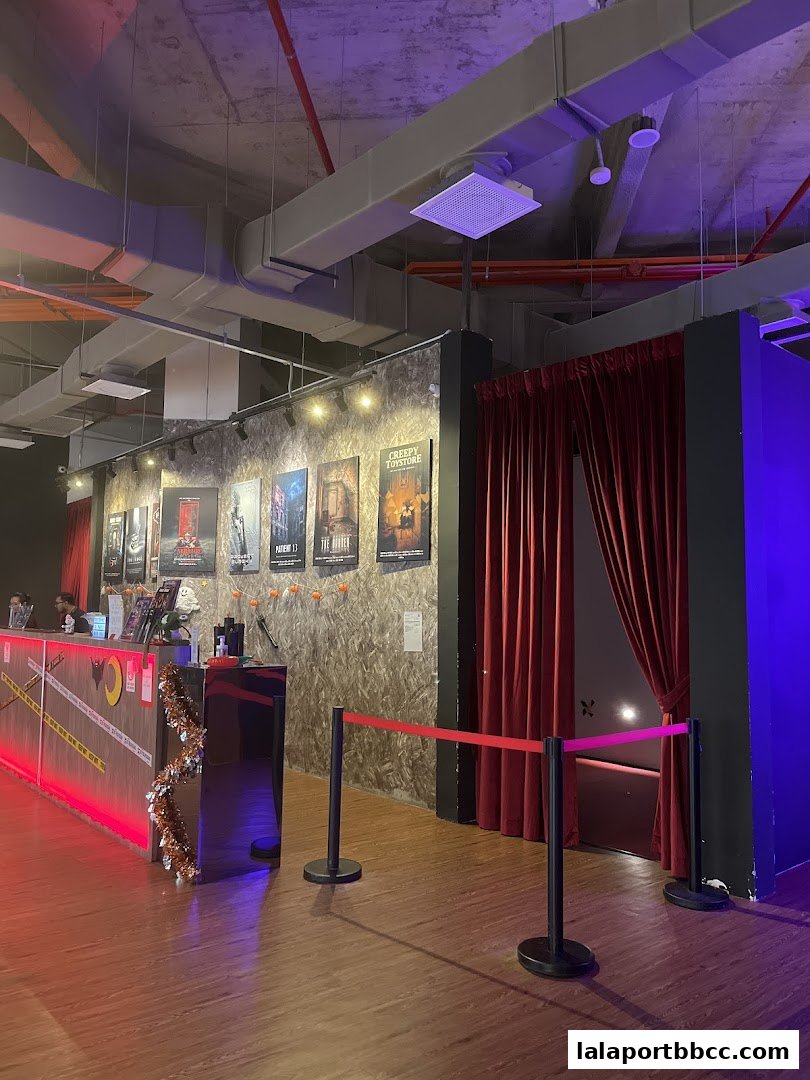 Interior of a themed attraction with posters, a counter, and velvet curtains.