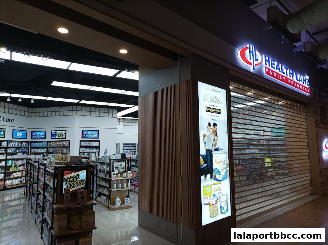 The exterior of Health Lane Family Pharmacy with its illuminated sign and closed roller shutters.