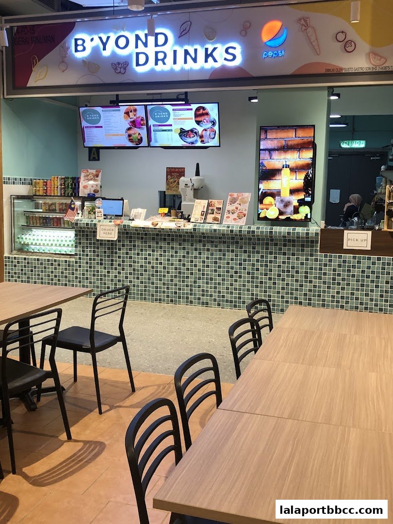 A brightly lit beverage shop counter with digital menus and seating area.