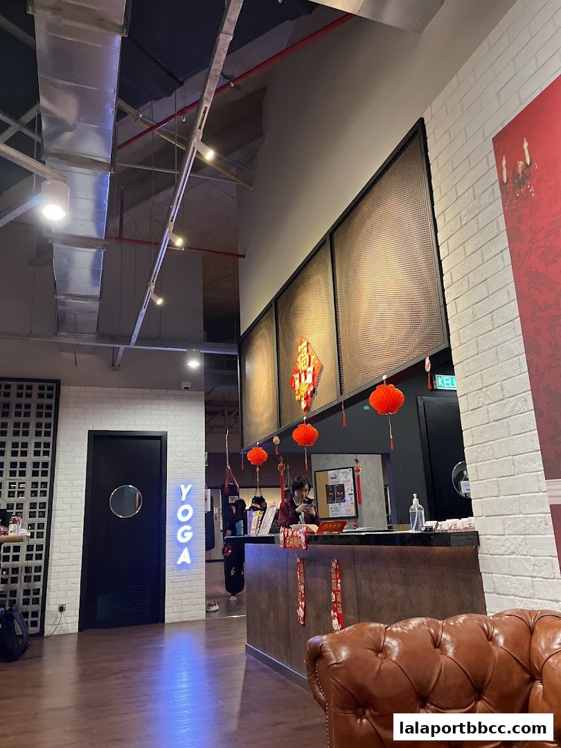 Interior view of a fitness studio with a reception desk, yoga sign, and punching bags.