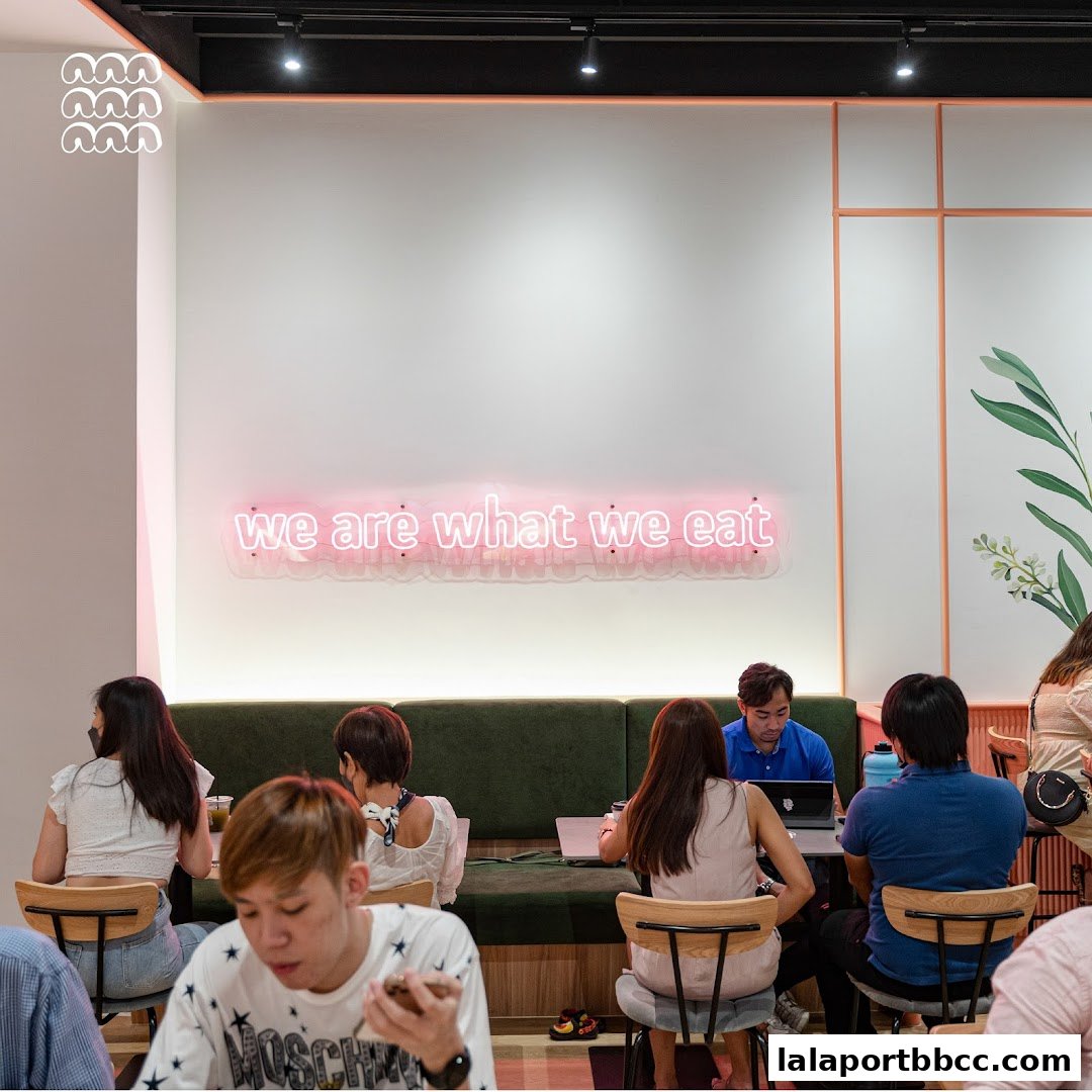 People dining and working inside a modern cafe with neon sign.