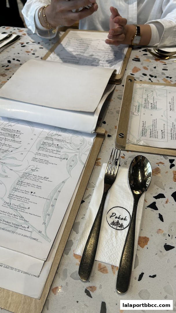 A table setting with menus, cutlery, and a napkin with the "Pokok" logo.