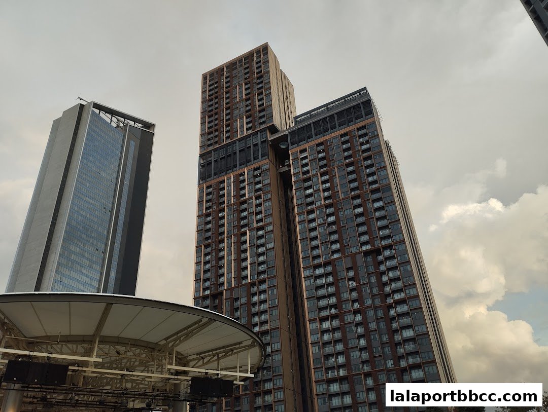 Tall modern buildings with many windows against a cloudy sky.