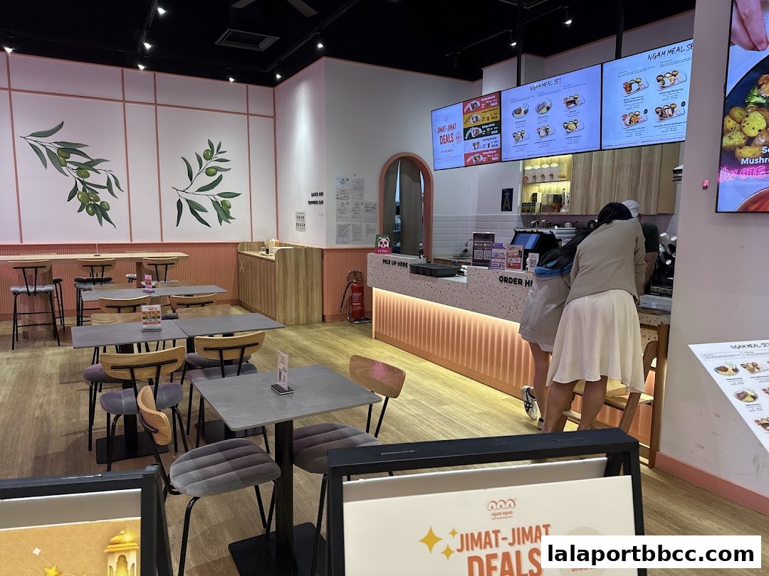 Interior of a modern restaurant with tables, chairs, and a counter with digital menus.