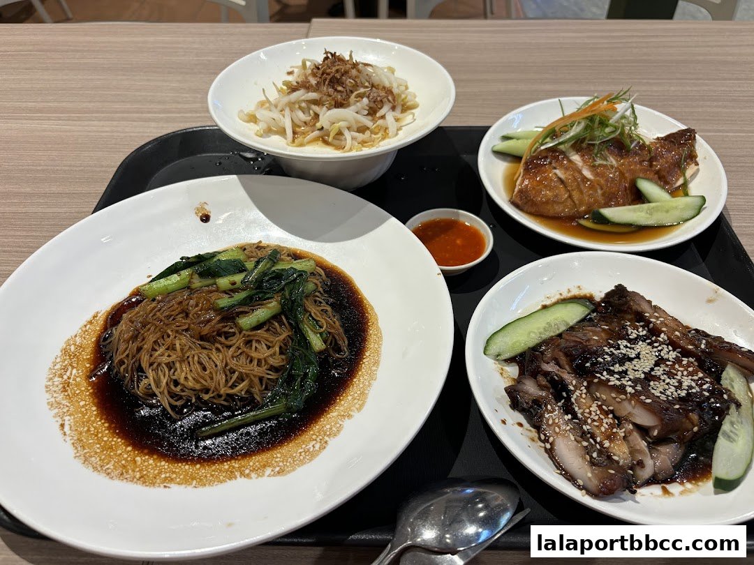 A tray of delicious chicken rice dishes, including roasted chicken, char siu, and noodles.