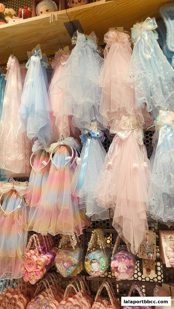 A display of colorful, sparkly accessories including headbands, bags, and sheer capes for children.