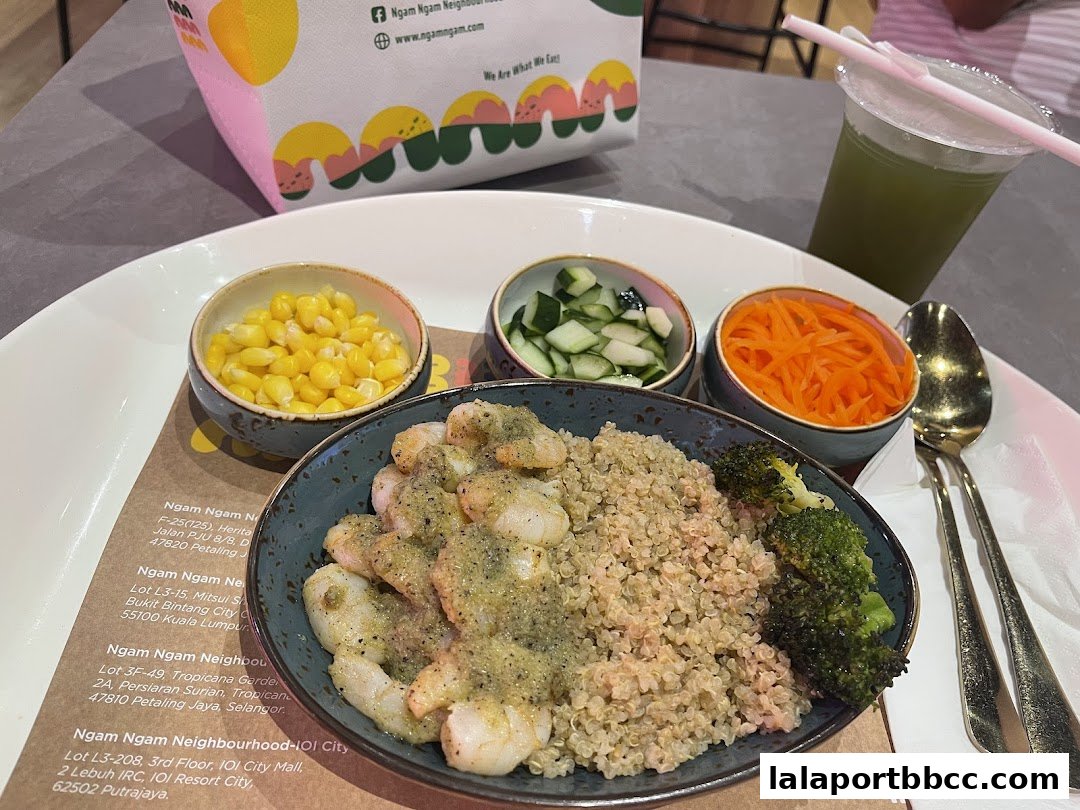 A healthy meal with quinoa, shrimp, broccoli, corn, cucumber, and carrots, served with a green drink.