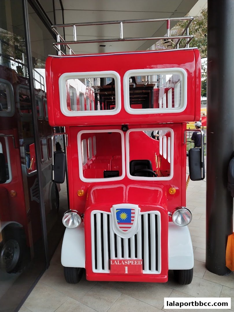 A bright red double-decker bus replica with a Malaysian flag emblem and 'LALASPEED 1' signage.