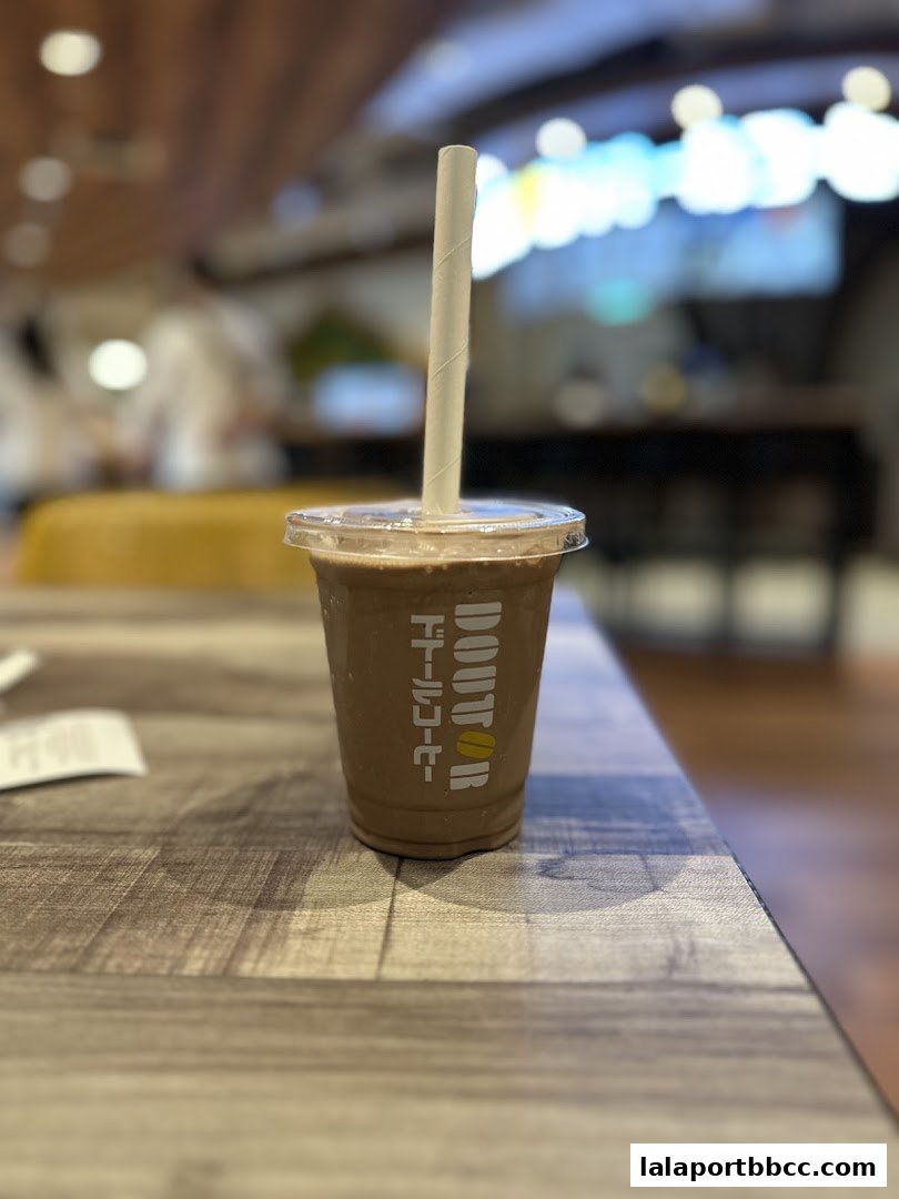 A close-up of a chocolate drink with a straw from Doutor Coffee on a wooden table.