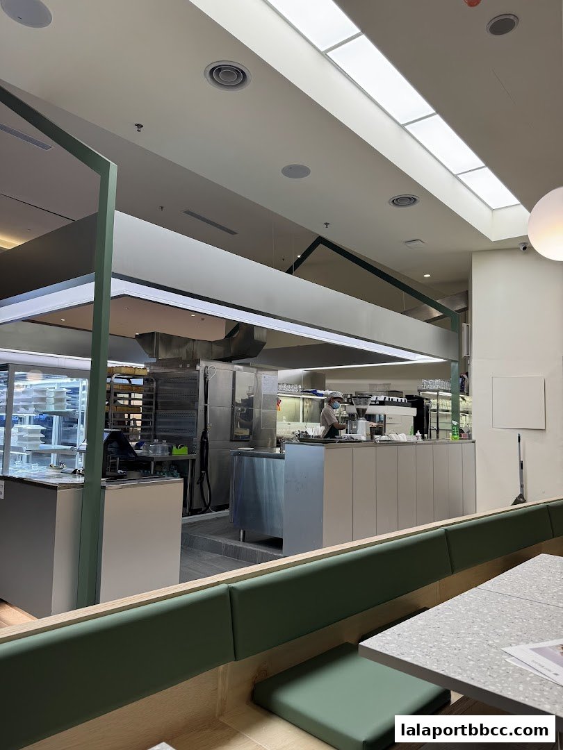 Interior view of a modern cafe with a visible kitchen and seating area.
