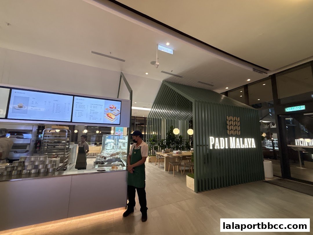 A modern cafe interior with a prominent PADI MALAYA sign and a digital menu board.