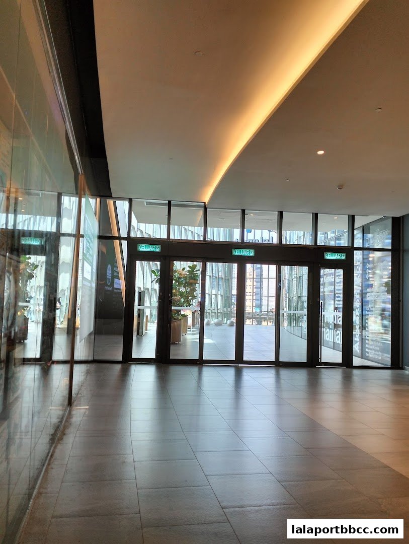 Modern shopping mall interior with glass doors and reflective floors.