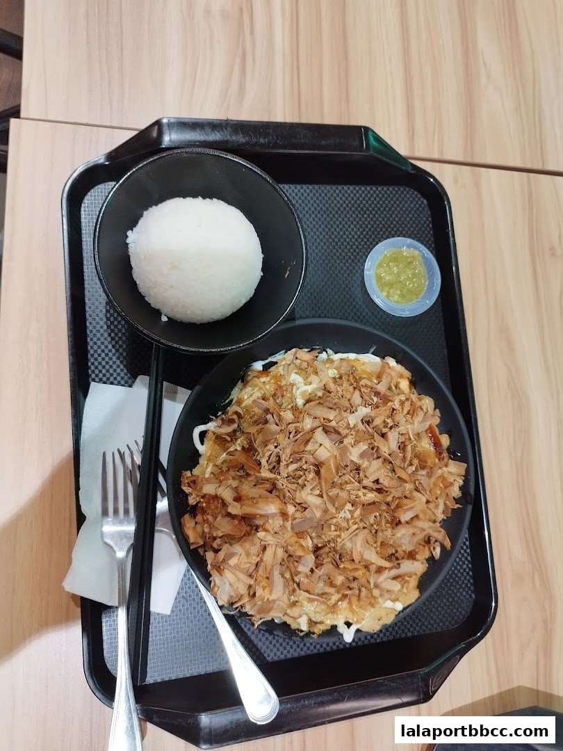 A delicious Japanese meal featuring rice, okonomiyaki, and a side of sauce.