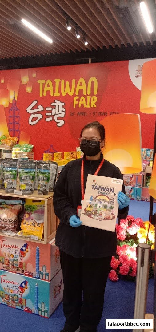A person in a mask and gloves holds a brochure at a Taiwan Fair event.
