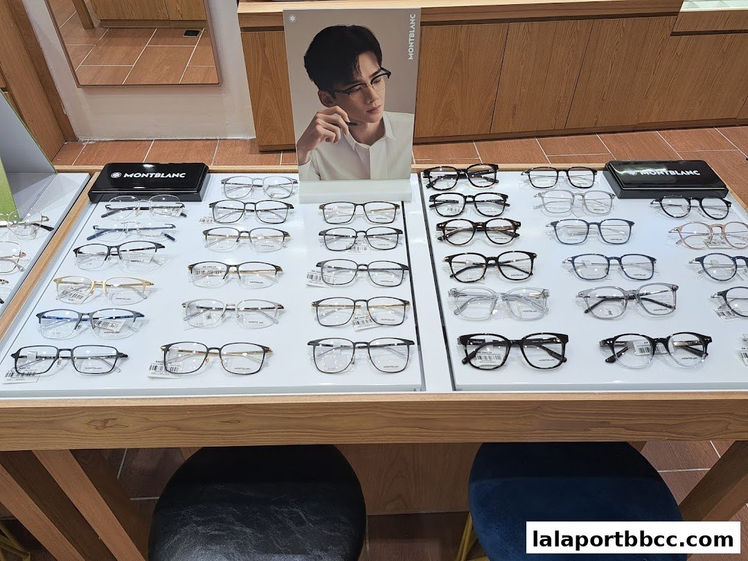 A display of various Montblanc eyeglasses on a wooden table with a promotional poster.