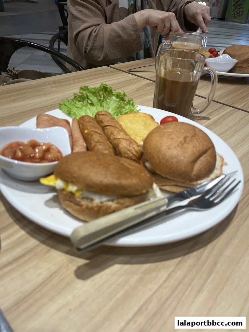 A hearty breakfast platter with burgers, sausages, baked beans, and a coffee.