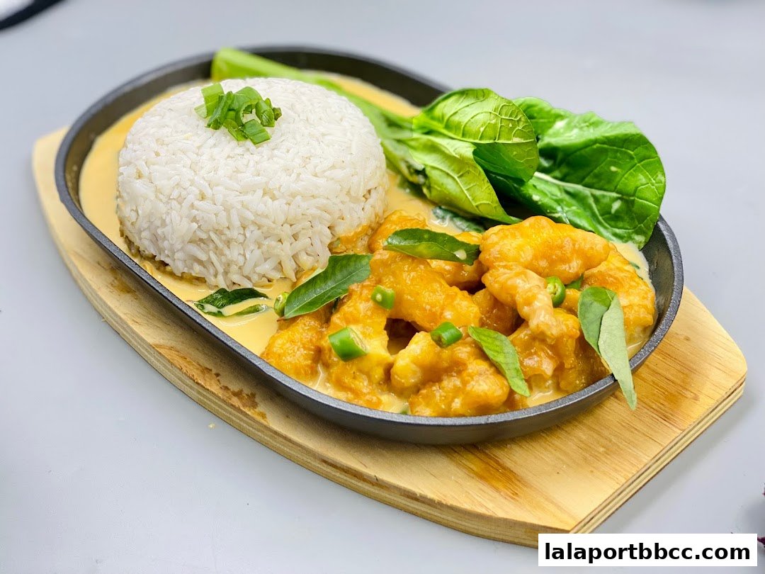 A sizzling platter of crispy fried chicken with creamy sauce, served with rice and greens.