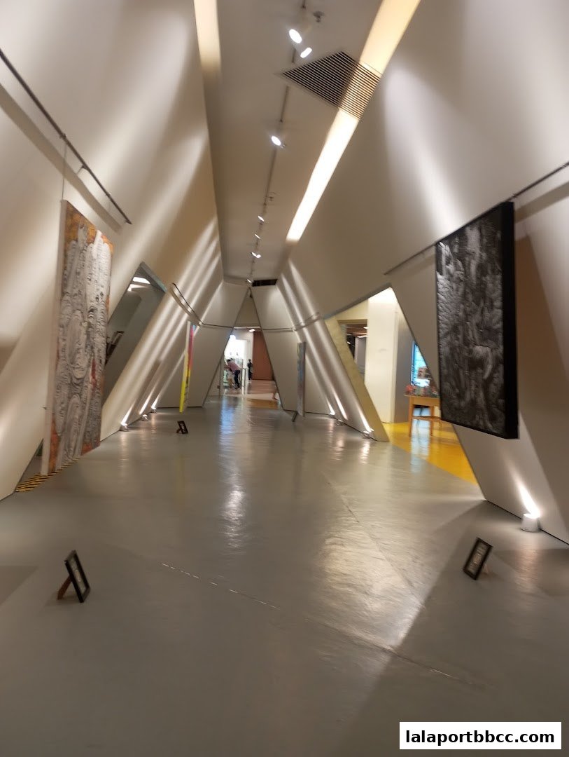 A modern hallway with abstract art displayed on the walls and dramatic lighting.