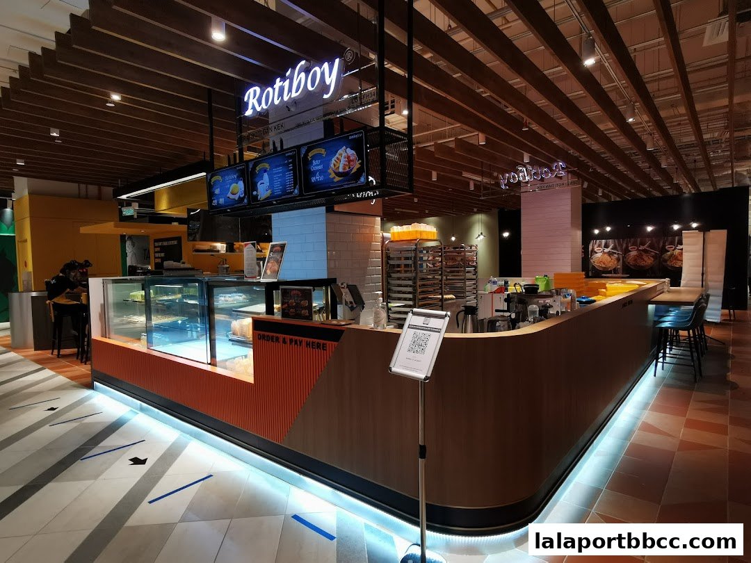 The interior of a Roti Boy bakery with a counter, display cases, and seating area.