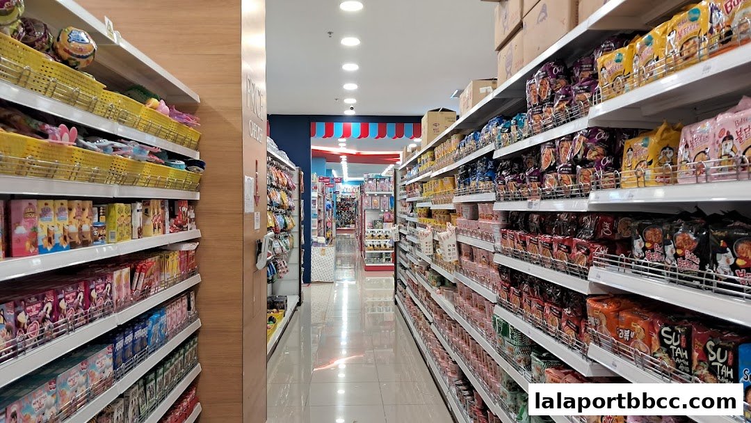A wide aisle in a brightly lit store filled with shelves of packaged snacks and toys.