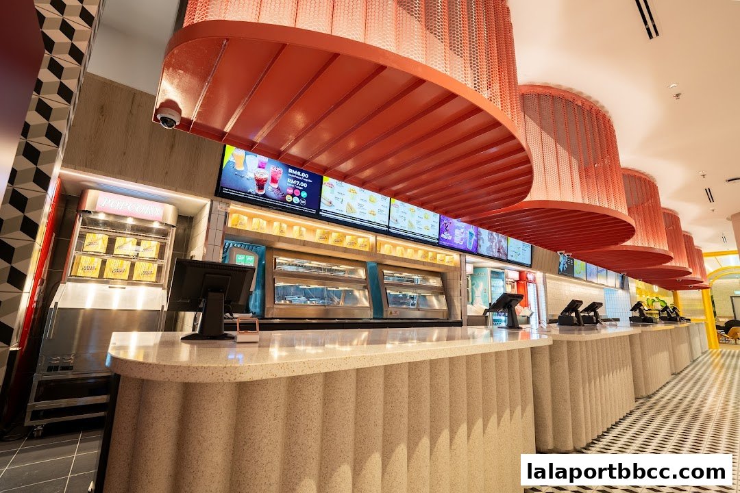 A modern food counter with digital menus, popcorn machine, and display cases.