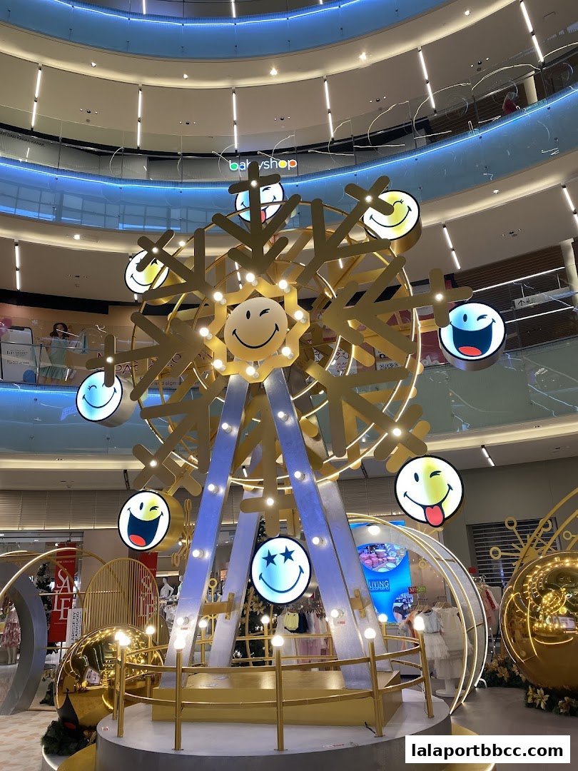 A festive Ferris wheel decoration with smiley faces inside a shopping mall.