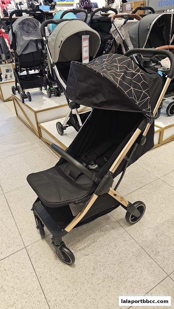 A stylish black stroller with gold accents is displayed in a retail store.