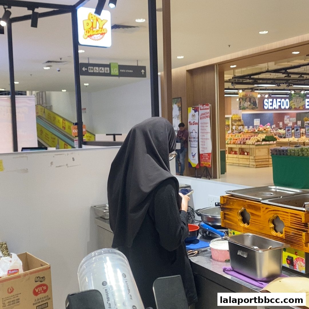 A person in a black hijab is working at a counter with cooking equipment.