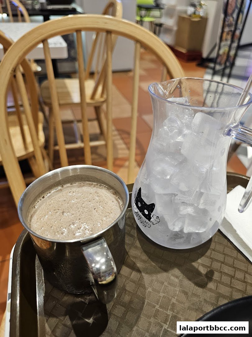 A close-up of a hot chocolate and a pitcher of ice water on a tray.