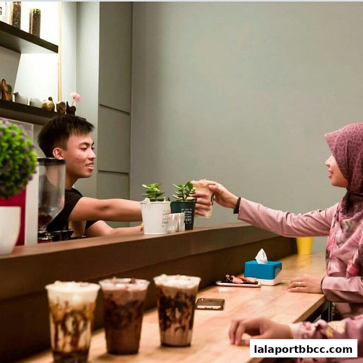 A barista hands a drink to a customer at a coffee shop counter.