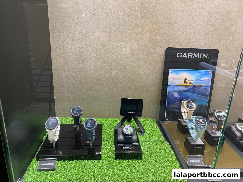 A display of Garmin smartwatches, including the Approach and Descent series, showcased on artificial grass.
