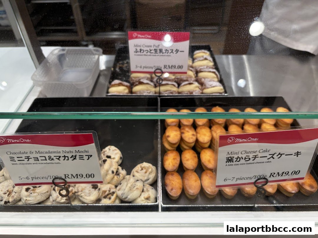 A display of freshly baked mini cakes and mochi at a bakery.