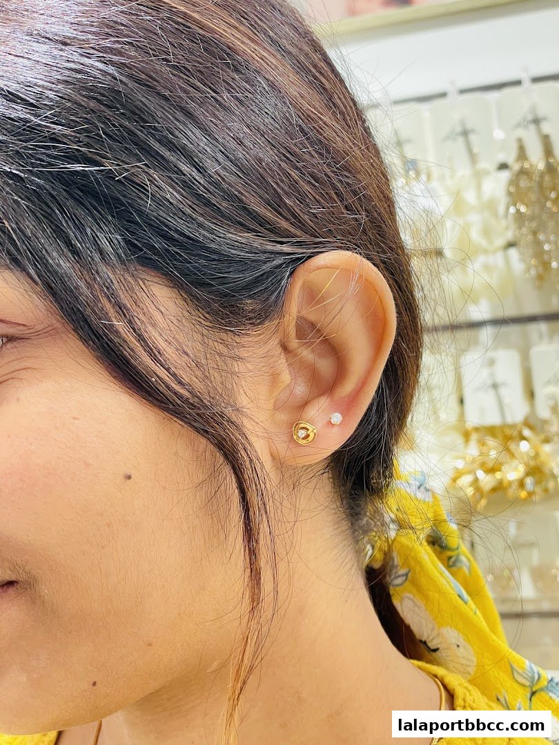 Close-up of a woman's ear showcasing delicate gold and diamond stud earrings.
