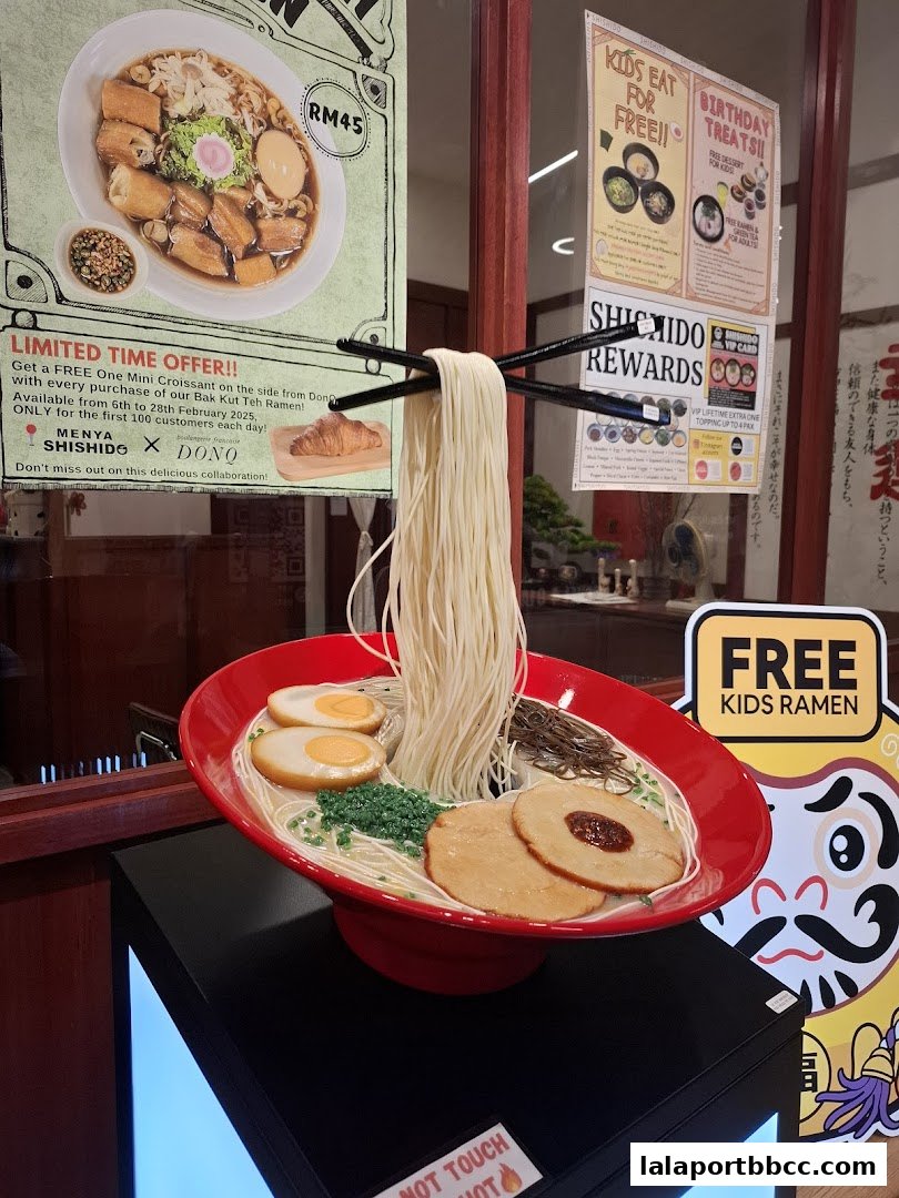 A realistic ramen display with chopsticks holding noodles, and promotional posters.
