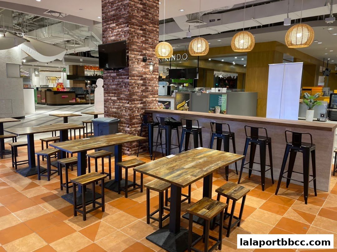 Interior view of a cafe with rustic wooden tables and chairs, and a counter with bar stools.