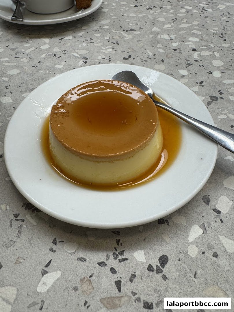 A close-up shot of a creamy crème caramel dessert with caramel sauce on a white plate.