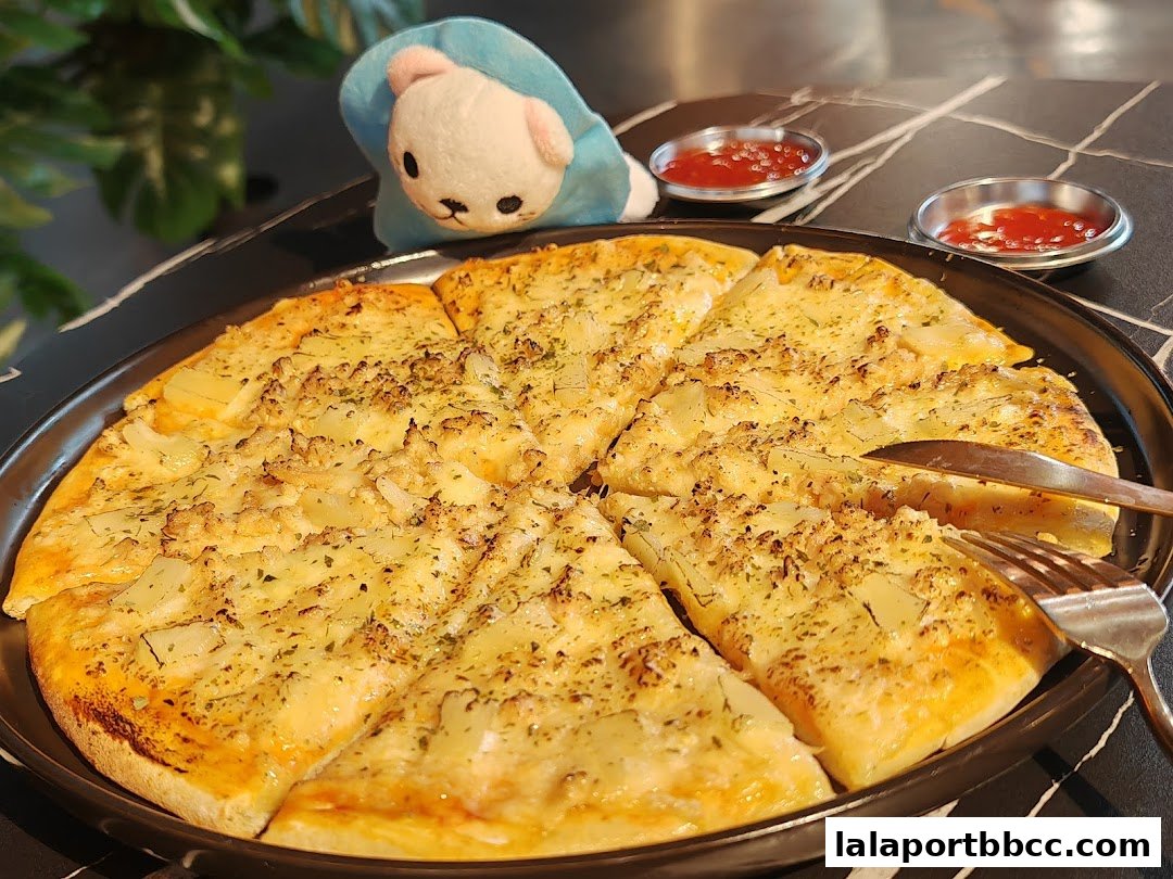 A delicious pizza with cheese and herbs, served with ketchup and a cute plush toy.